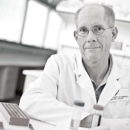 Black and white image or researcher sitting in a lab.